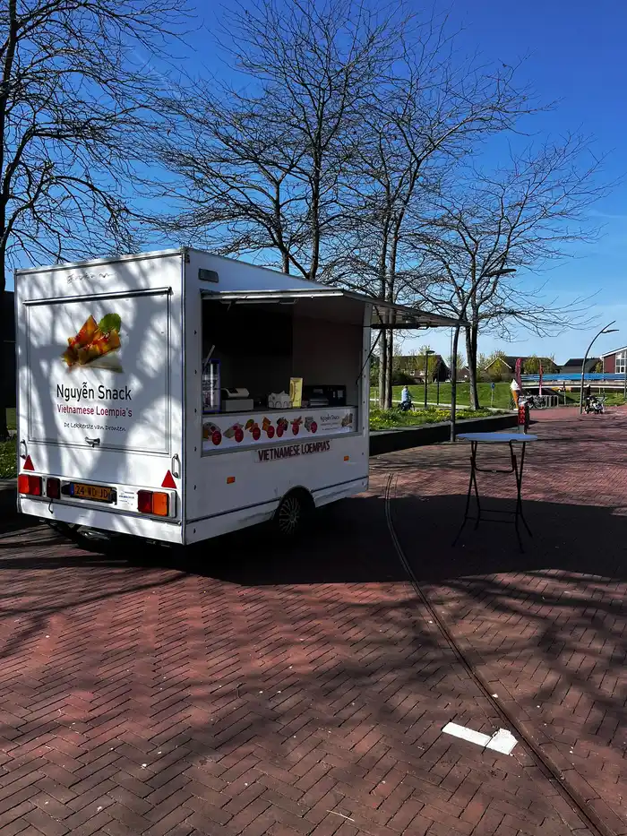 Zijkant van de Nguyễn Snack foodtruck met Vietnamese loempia's op het plein in Dronten West